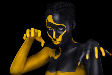 Wall Mural - Face art. Woman with black and yellow body paint. Young african girl with colorful bodypaint. An amazing model with yellow makeup. Closeup face.