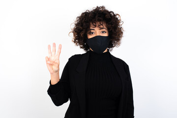 Sticker - young beautiful caucasian woman wearing medical mask standing against white wall, showing and pointing up with fingers number three while smiling confident and happy.