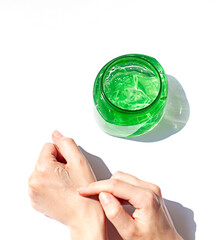 After sun cooling skin cosmetics. Woman is testing or applying aloe vera gel in a transparent jar top view.	