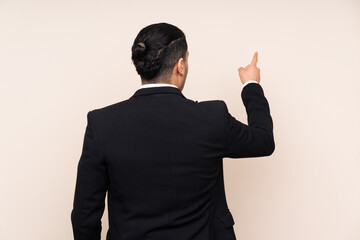 Wall Mural - Asian business man isolated on beige background pointing back with the index finger