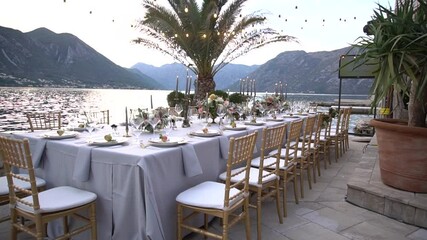Wall Mural - A table at a wedding banquet, decorated with flowers, candlesticks and young pomegranates on the pier in the Bay of Kotor