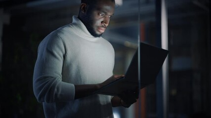 Aufkleber - Handsome Black African American Male is Standing in Meeting Room Behind Glass Walls with Laptop Computer in an Creative Agency. Project Manager Wearing White Jumper and Working on App User Interface.