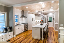 Large Renovated White Kitchen With Textured Subway Tile, Black Iron Lights And Pine Hardwood Flooring