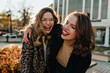 © Look! - Adorable curly girl chilling with friend outdoor. Gorgeous female models posing on the street in autumn.