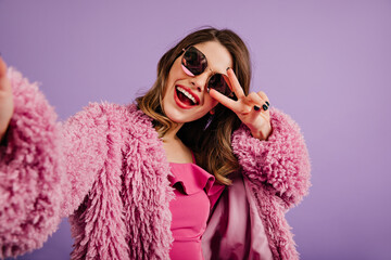 Poster - Charming stylish woman posing with smile. Caucasian girl making selfie in purple coat.