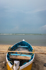 Fishing boat with fishing net on the yellow sandy beach with clouds and blue sky