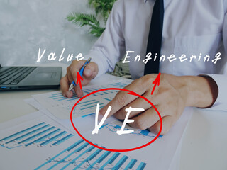 Conceptual photo about VE Value Engineering with written abbreviation. Business Man Checking Documents on background.