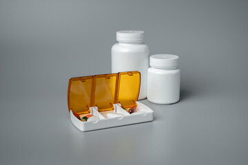 Wall Mural - Pills and capsules in pill organizer. Medical Concept, Illustration of Pharmacy Bag with Pill Container or Pill Box on gray background. 
Disease prevention. 