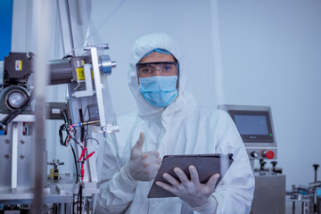 Technician worker wearing protective suite , glove are inspect ion with check  face mask manufacturing process to safe and against from virus. 