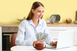 © Pixel-Shot - Beautiful woman with money, rugby ball and laptop in kitchen. Concept of sports bet