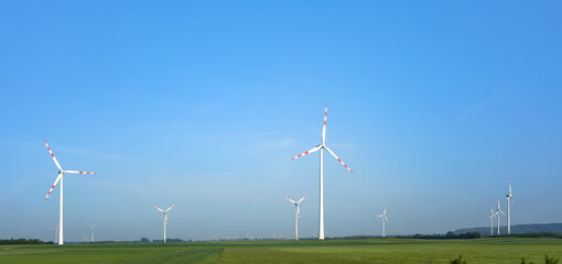 Wall Mural - green fields with wind power turbines, clear blue sky above