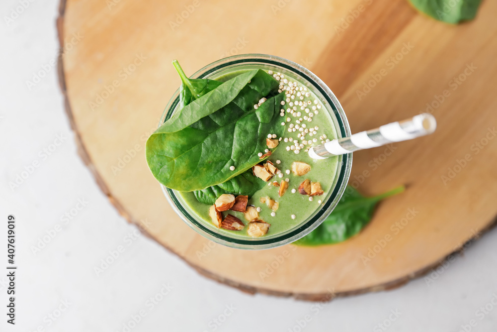 Glass of healthy spinach smoothie on light background