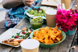 © simona - Close up of table full of colorful mexican food like nachos and guacamole or pizza - concept of people eat together and celebrate