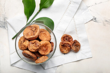 Bowl with tasty dried figs on light background