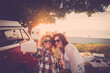 © simona - Couple of female friends enjoy and have fun together taking selfie in outdoor - vintage red van and sunlight in background - alternative people women in friendship smile at the park