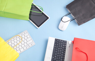 Wall Mural - Computer keyboard, tablet, mouse and shopping bags on the blue background.