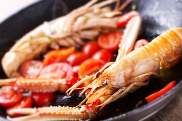 Wall Mural - Scampi, preparation and cooking in a pan. Shellfish scampi cooked in a pan with cherry tomatoes