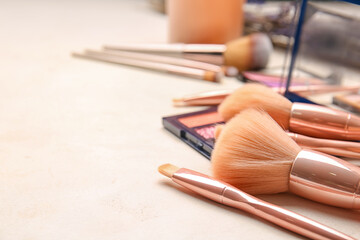 Set of makeup brushes with cosmetics on table