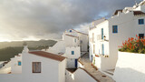 Fototapeta  - White houses during sunset in Nerja Village, located within a green hill landscape in Andalusia, Spain.