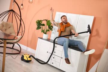 Sticker - Young man having fun while vacuuming at home