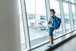 © Soloviova Liudmyla - Lonely teen solo traveler with backpack standing in the empty airport passenger transfer hall in protective face mask and looking out large windows. Traveling in worldwide pandemic time concept image