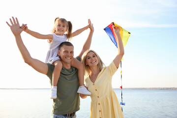 Poster - Happy parents with their child playing with kite on beach. Spending time in nature