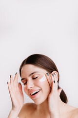 Sticker - Attractive brunette enjoying spa procedure on isolated background. Smiling girl applies moisturizer