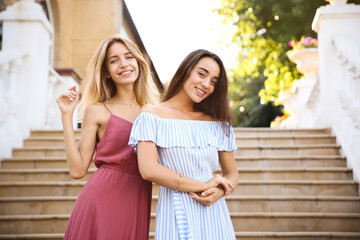 Sticker - Beautiful young women in stylish dresses on stairs outdoors