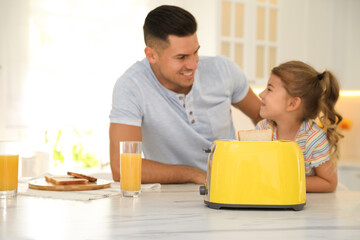 Poster - Father and daughter near modern toaster at kitchen table