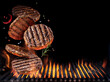 Grilled beef steaks in motion falling down on open grill. Conceptual photo of meat or barbeque cooking process.