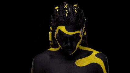 Wall Mural - Face art. Dancing woman with black and yellow body paint. Young african girl with colorful bodypaint. An amazing afro american model with yellow makeup. Closeup face.