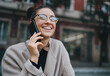 © Roman - Young lovely smiling Caucasian woman speaking on her smartphone while having walk in the city. Concept of using mobile devices for communication and interaction. Good vibes and positive emotions