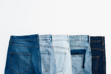 Wall Mural - horizontal row of different blue jeans isolated on white, top view