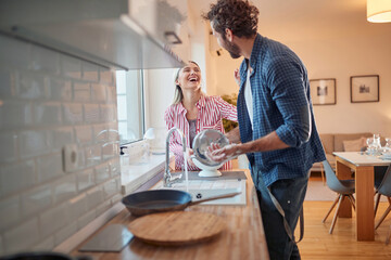 Joyful couple doing the dishes together