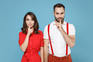 Sticker - Secret young couple two friends man woman in white red clothes saying hush be quiet with finger on lips shhh gesture isolated on blue background studio portrait. St. Valentine's Day holiday concept.