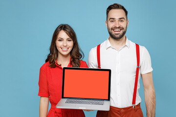 Wall Mural - Smiling young couple two friends man woman in white red clothes hold laptop pc computer with blank empty screen isolated on pastel blue color background studio. St. Valentine's Day holiday concept.