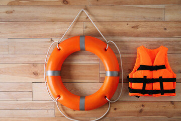 Orange life jacket and lifebuoy on  wooden background. Rescue equipment