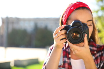 Young photographer taking picture with professional camera outdoors. Space for text