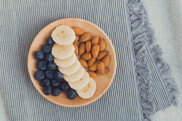 Healthy snack dish flat lay - banana, blueberries, almond gray background