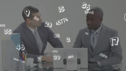 Sticker - Digital animation of multiple changing numbers and symbols against two businessman using laptop