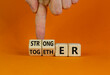 Stronger together symbol. Businessman turns cubes and changes the word together to stronger. Beautiful orange background, copy space. Business, motivational and stronger together concept.