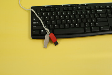 Wall Mural - Top view of a computer keyboard and USB flash drives on it displayed on a yellow background