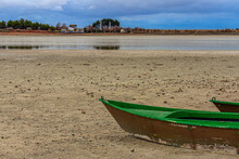 Closeup Of An Old Green Fishing Boat On A Sandy Shore Of A Lake