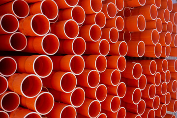 Stacked orange electrical conduit pipes making a pattern of circles.