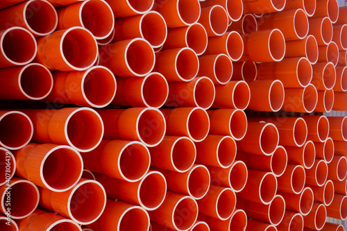 Stacked orange electrical conduit pipes making a pattern of circles.