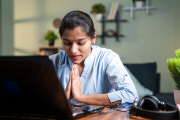 young business woman praying in front of laptop after completion of online test or examination for results - Concept of believe, gratitude in god.