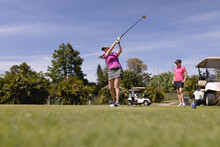 Two Caucasian Women Playing Golf One Swinging Club And Taking A Shot