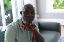 Portrait Of Senior African American Man Sitting In Living Room Leaning On Walking Stick
