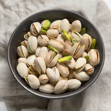 Salted Pistachios Nuts In Dark Bowl. Healthy Vegetarian Protein Nutritious Food. Natural Nuts Snacks.