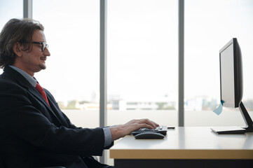 Caucasian businessman wearing suit working with computer at the office.